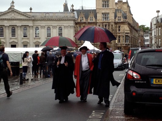 Dons walking in the rain at Cambridge graduation.